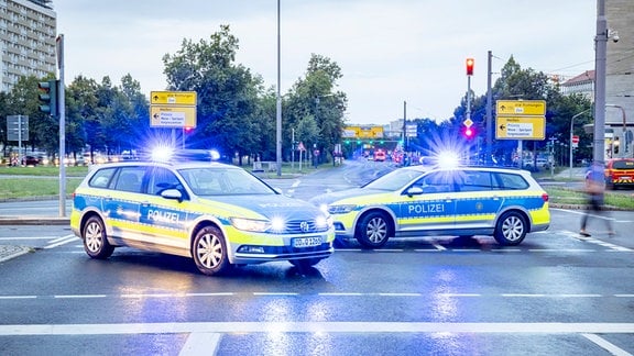 Zwei Polizeifahrzeuge stehen mit Blaulicht auf der Straße.