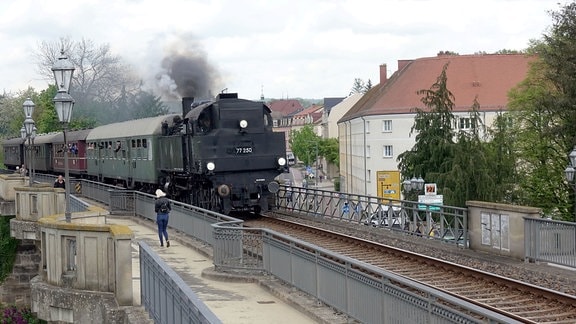 Eine Dampflokomotive fährt über eine Brücke.