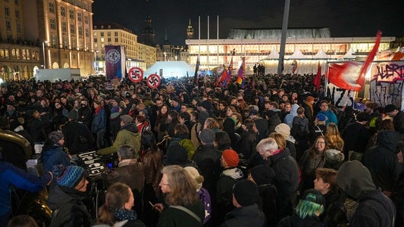 Menschen haben sich zu einer Demo auf dem Altmarkt in Dresden versammelt, es ist Dunkel