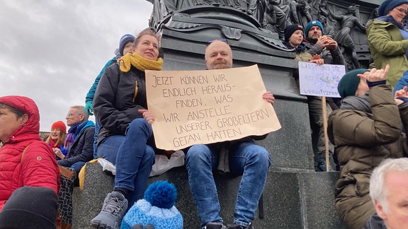 Teilnehmer bei Demo Dresden halten ein Plakat hoch