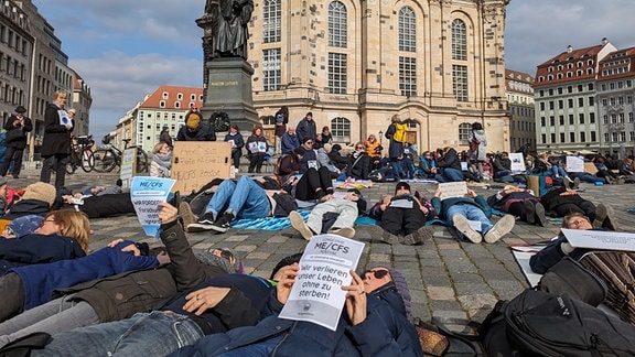 Menschen liegen auf dem Boden vor der Frauenlirche in Dresden.