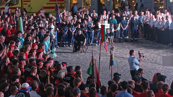 Junge Feuerwehrleute aus ganz Deutshland stehen in Dresden in neumarkt vor einer großen Bühne.