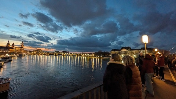 Menschen stehen auf einer Brücke und schauen auf die Altstadt von Dresden.