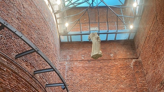 Blick in eine Ausstellungshalle, in der eine Skulptur in der Luft hängt. 