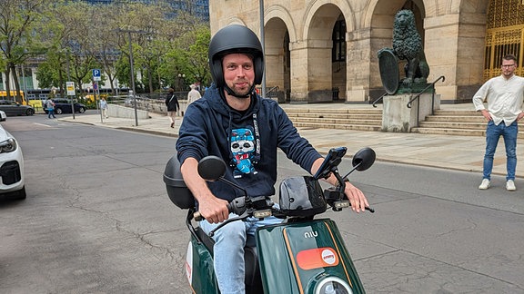 Mann sitzt auf einem Elektro-Moped