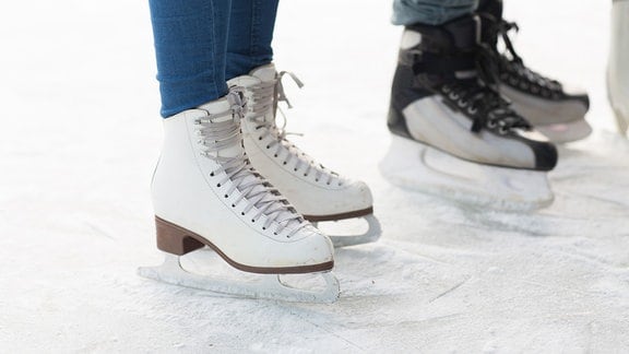 Füße in Schlittschuhen auf dem Eis
