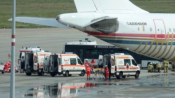 Drei Krankenwagen stehen neben einem Flugzeug.