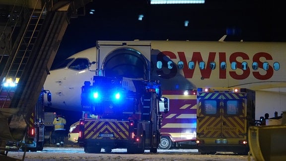 Feuerwehrautos und ein Krankenwagen stehen vor dem Airbus am Flughafen Dresden.