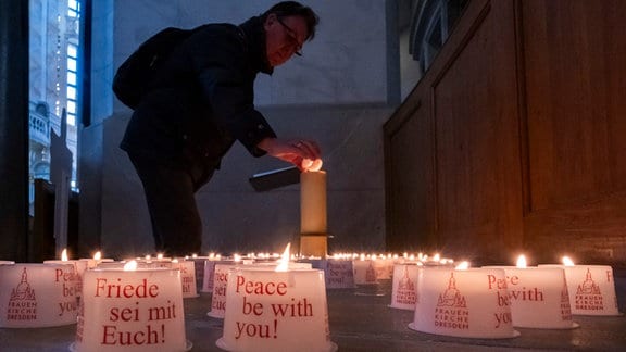 Ein Kirchenbesucher zündet eine Kerze in der Frauenkirche an. In der Stadt finden den ganzen Tag Gedenkveranstaltungen in Erinnerung an den 79. Jahrestag der Bombardierung von Dresden statt.