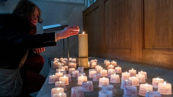 Eine Kirchenbesucherin zündet eine Kerze in der Frauenkirche an. In der Stadt finden den ganzen Tag Gedenkveranstaltungen in Erinnerung an den 79. Jahrestag der Bombardierung von Dresden statt.