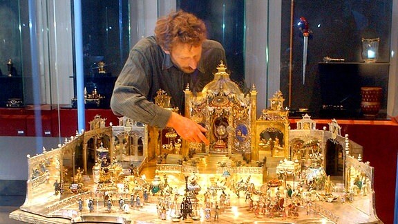 Der Restaurator Rainer Richter hebt im Neuen Grünen Gewölbe der Staatlichen Kunstsammlungen Dresden die Figur des Großmoguls Aureng-Zeb in seinen Miniaturhofstaat.