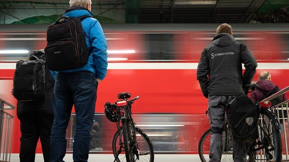 Reisende an einem Bahnsteig, während eine S-Bahn einfährt