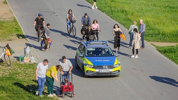 Menschen und ein Polizeiauto unterwegs am Dresdner Elbufer