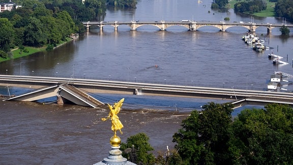 Die Hochwasser führende Elbe fließt an der zum Teil eingestürzten Carolabrücke entlang, im Vordergrund ist der Engel «Fama» auf der Kunstakademie zu sehen.