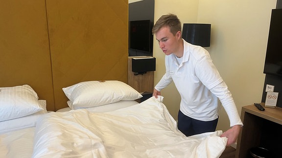 Ein Mitarbeiter faltet einen Bettdecke.