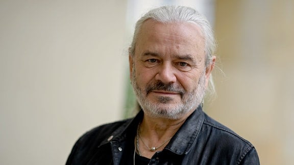 Jäcki Reznicek, ein Mann mit Sieben-Tage-Bart, grauen Haaren und Lederjacke schaut in die Kamera.