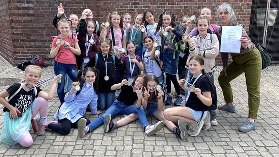 Eine Mädchen-Tanzgruppe des Heinrich-Schütz-Konservatoriums Dresden präsentiert Medaillen für die Choreografie "Ein Schultag".