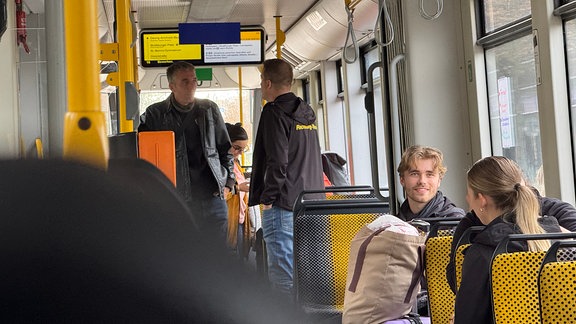 Mehrere Menschen in einer Straßenbahn.