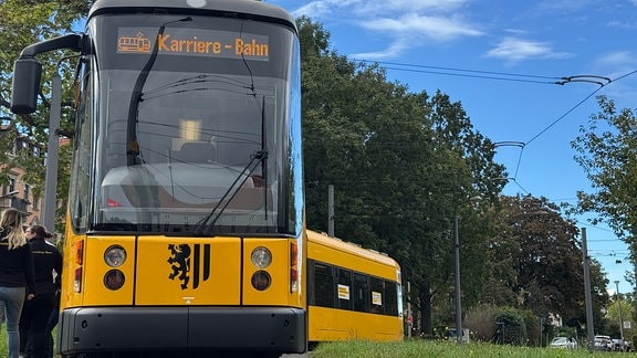 Eine Straßenbahn an einer Haltestelle.