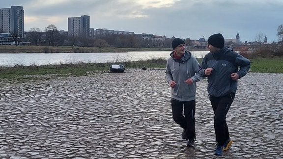 Zwei Männer laufen an der Elbe entlang.