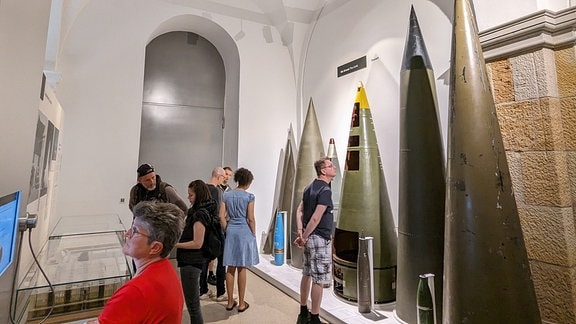 Mehrere Besucher stehen vor Sprengköpfen von Atomrakten in einem Militärmuseum