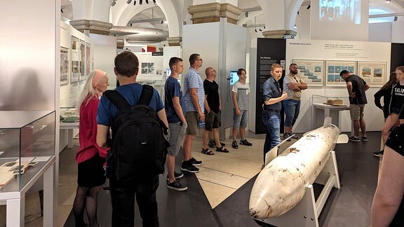 Mehrere Besucher stehen vor der Hülle einer Atombombe in einem Militärmuseum