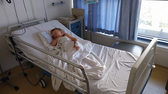 Ein kleiner Junge liegt in einem Krankenhausbett