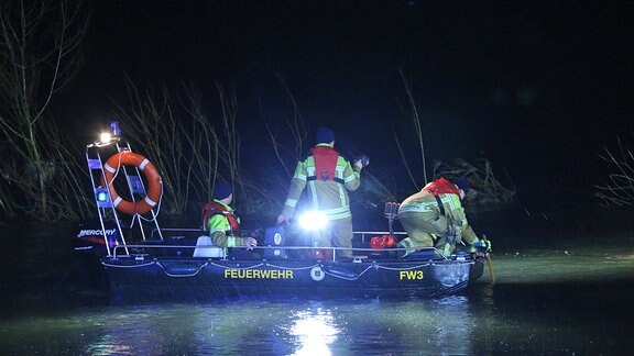 Feuerwehrleute suchen in einem Rettungsboot bei Dunkelheit nach einem Pkw