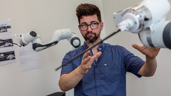 Andreas Gundlach mit einem Roboterarm