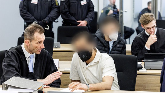 Angeklagter Mohamed R. (vordere Reihe r) und Angeklagter Bashir R. (2. Reihe, 2. r) sitzen neben ihren Anwälten im Gerichtssaal des Oberlandesgerichts Dresden.