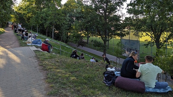 Einige Frauen und Männer sitzen auf einem Hang. 