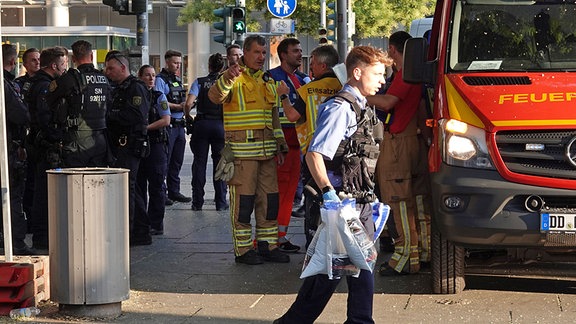 Polizei und Einsatzkräfte der Feuerwehr stehen in der Innenstadt von Dresden, am Ort, wo sich die Schlägerei abgespielt hatte.