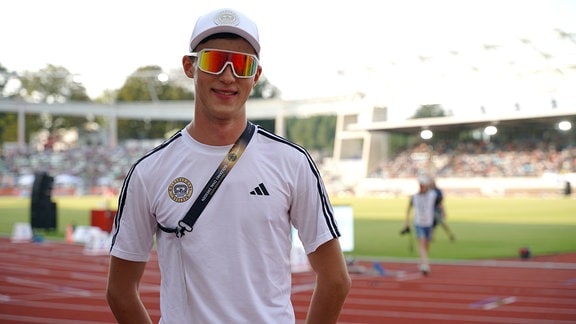 Eine junger Mann mit sportlicher Brille schaut freundlich in die Kamera.