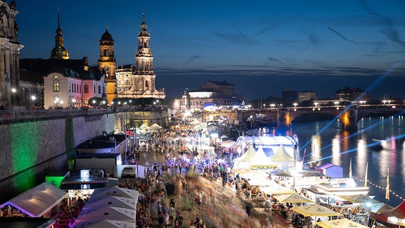 Besucher gehen beim Dresdner Stadtfest vor der Kulisse der Altstadt am Terrassenufer entlang