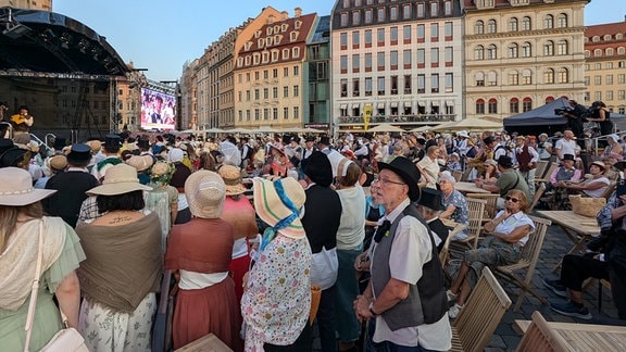 Viele kostümierte Menschen vor einer Bühne. 