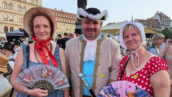 Zwei kostümierte Frauen und ein kostümierter Mann. 