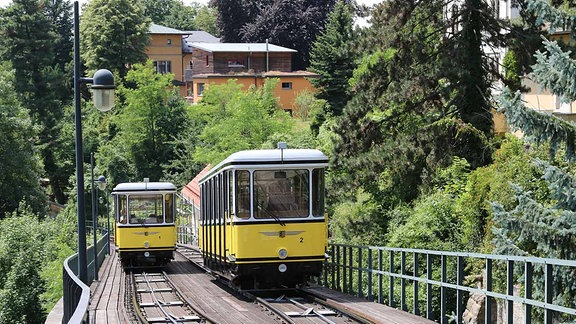 Zwei Standseilbahnen fahren auf den Schienen in Dresden.