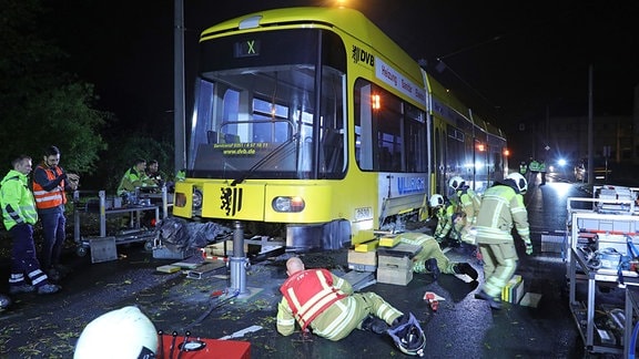 Einsatzkräfte heben mit Technik eine Straßenbahn wieder ins Gleis.