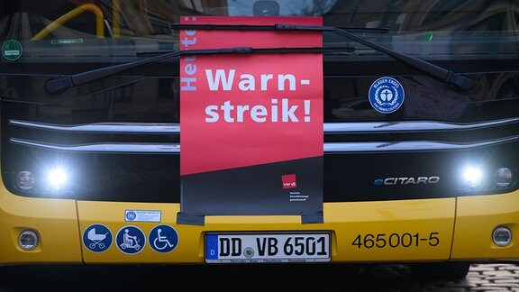 Ein Plakat «Warnstreik» ist an einem Bus der Dresdner Verkehrsbetriebe (DVB) während des Warnstreiks im öffentlichen Nahverkehr im Betriebshof Trachenberge unter den Scheibenwischer geklemmt.