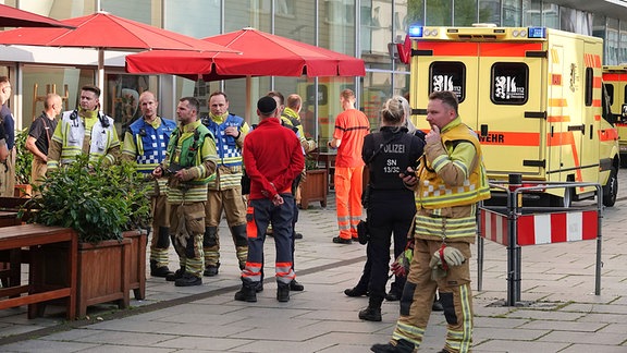 Zahlreiche Einsatzkräfte von Polizei und Feuerwehr stehen vor einem Restaurant in der Dresdner Innenstadt.