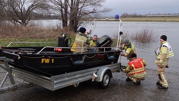 Rettungskräfte lassen ein Motoboot zu Wasser.