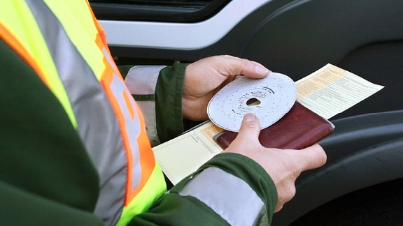 Polizist kontrolliert einen Fahrtenschreiber