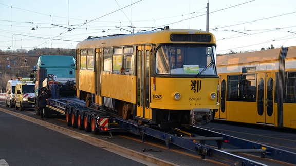 Eine gelbe Tatra-Bahn wird auf einen Tieflader gezogen.