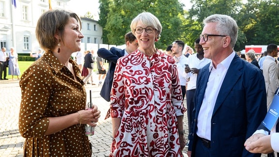Dörte Dinger (l), Chefin des Bundespräsidialamts, begrüßt Thomas de Maiziére und seine Frau Martina de Maizière beim Bürgerfest von Bundespräsident Steinmeier im Park von Schloss Bellevue.