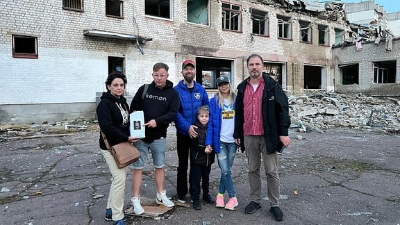 Menschen stehen vor einem zerbombten Haus in Shytomyr (Ukraine), es ist eine Schule
