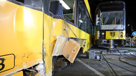 Zwei durch einen Unfall Straßenbahnen stehen versetzt nebeneinander. An beiden Bahnen sind Schäden zu sehen. 