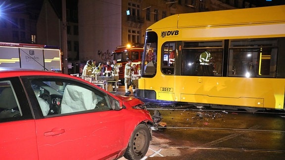 Ein rotes Auto und eine gelbe Straßenbahn stehen nach einem Zusammenstoß auf einer Straße.