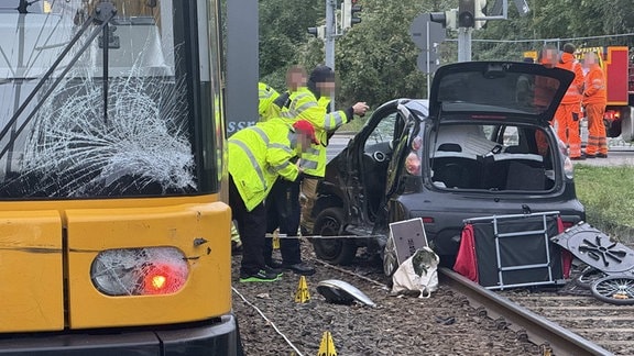 Rettungskräfte sichern ein mit einer Straßenbahn kollidiertes Auto ab.