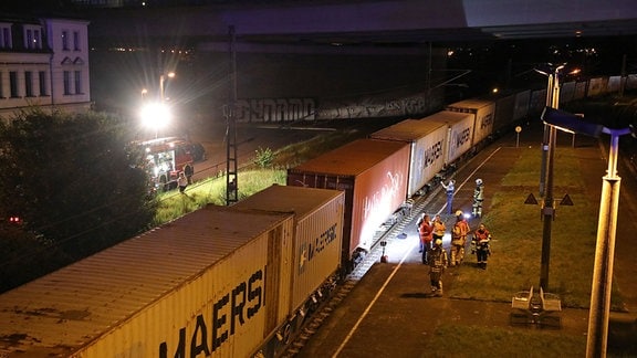 Rettungskräfte stehen am Gleis bei einem Güterzug.