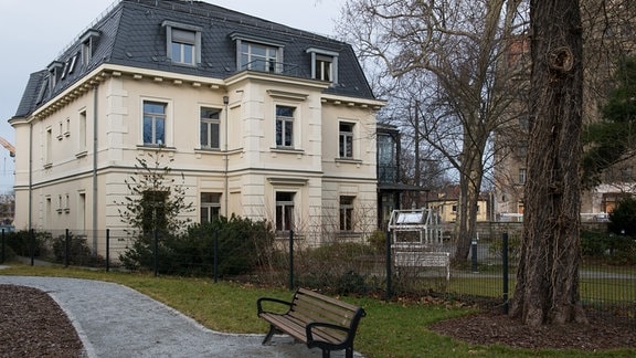 Das Erich-Kästner-Museum, eine zweistöckige Villa mit heller Fassade, davor ein Park mit einer Bank 